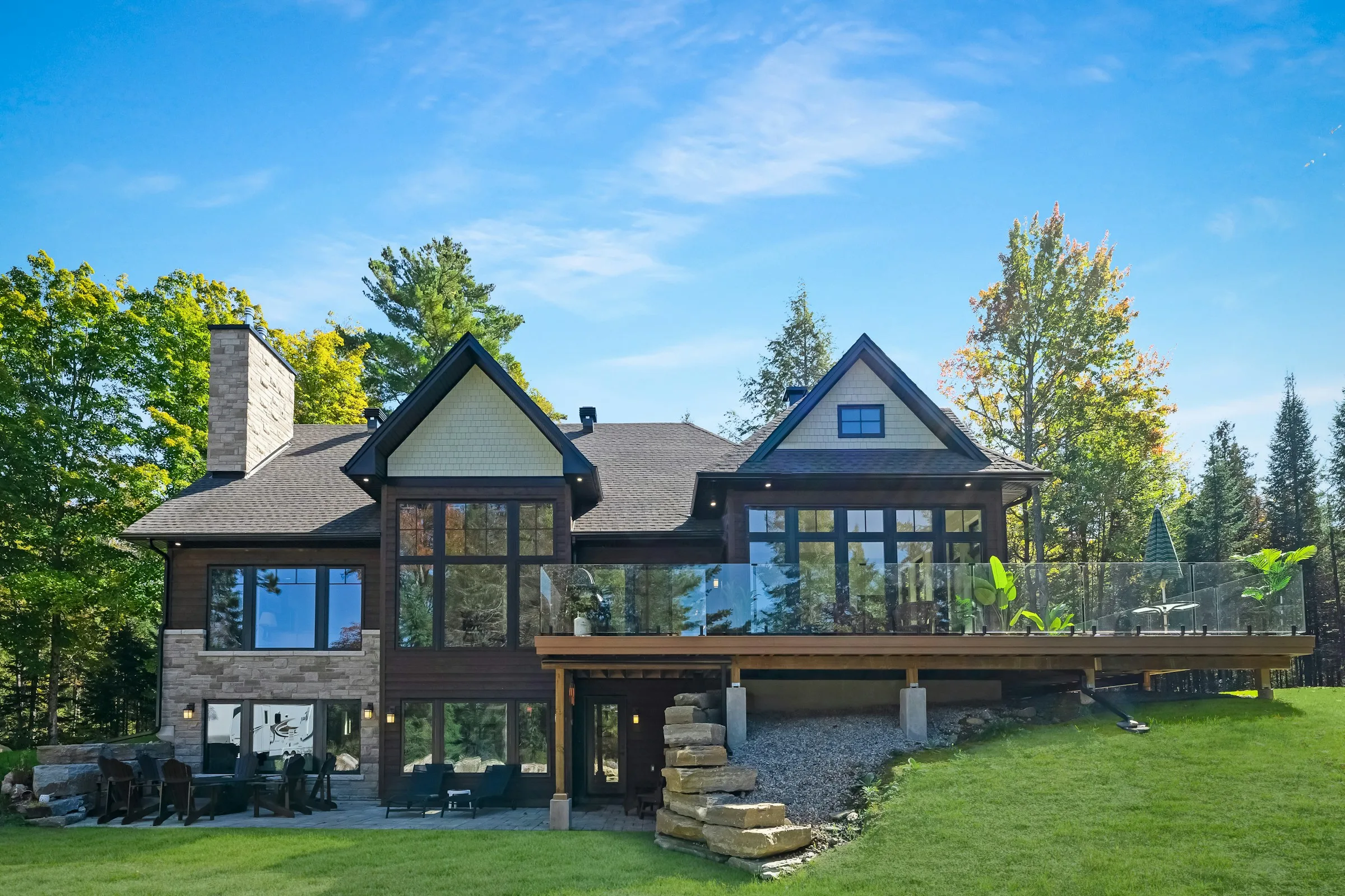 Large timber and stone home in the woods with a wide raised deck across the back