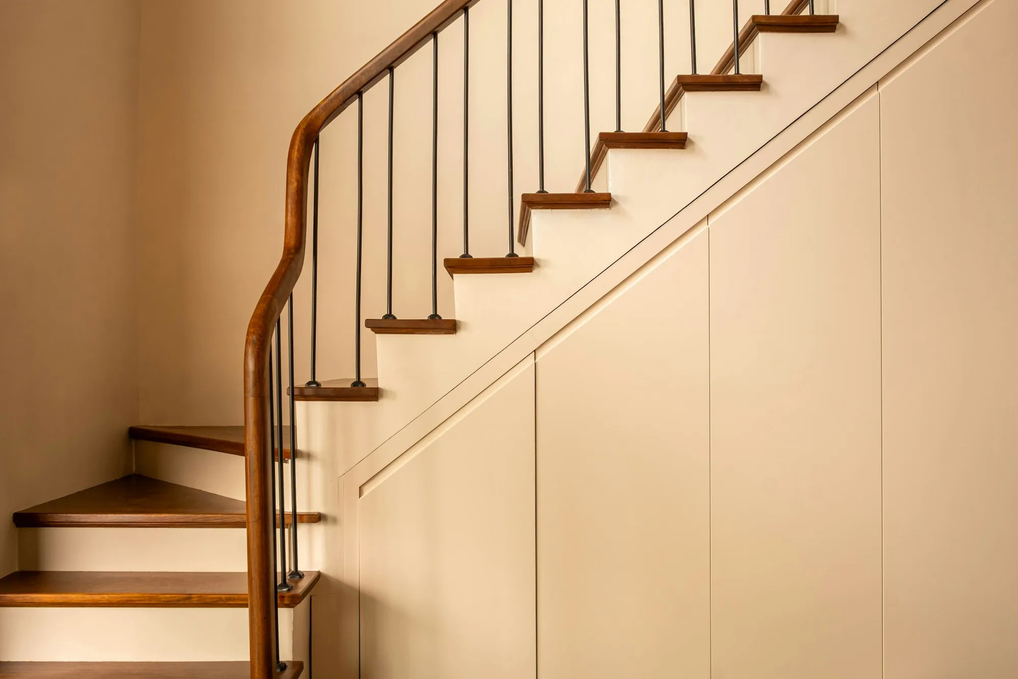 Interior staircase with wood treads and handrail above a painted paneled wall