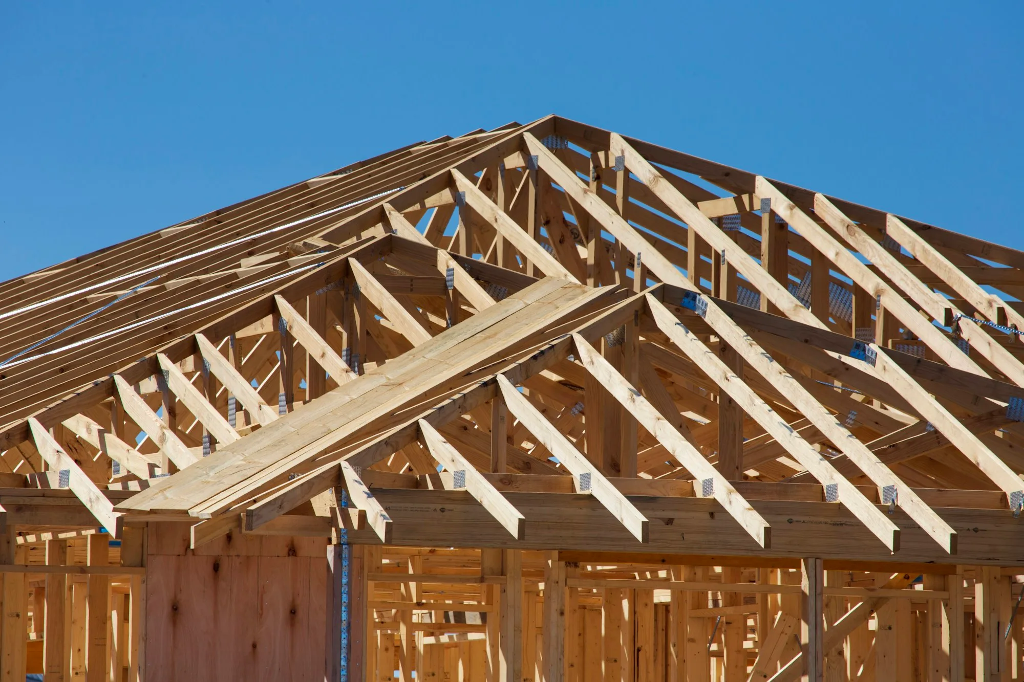 Roof truss framing of a house under construction, bare timber against an open sky
