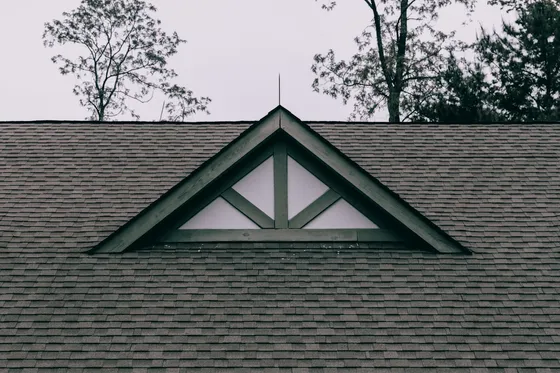 Dark asphalt shingle roof with a decorative triangular gable truss and white trim