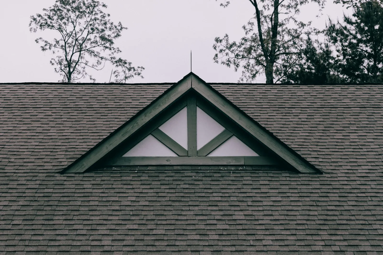 Dark asphalt shingle roof with a decorative triangular gable truss and white trim